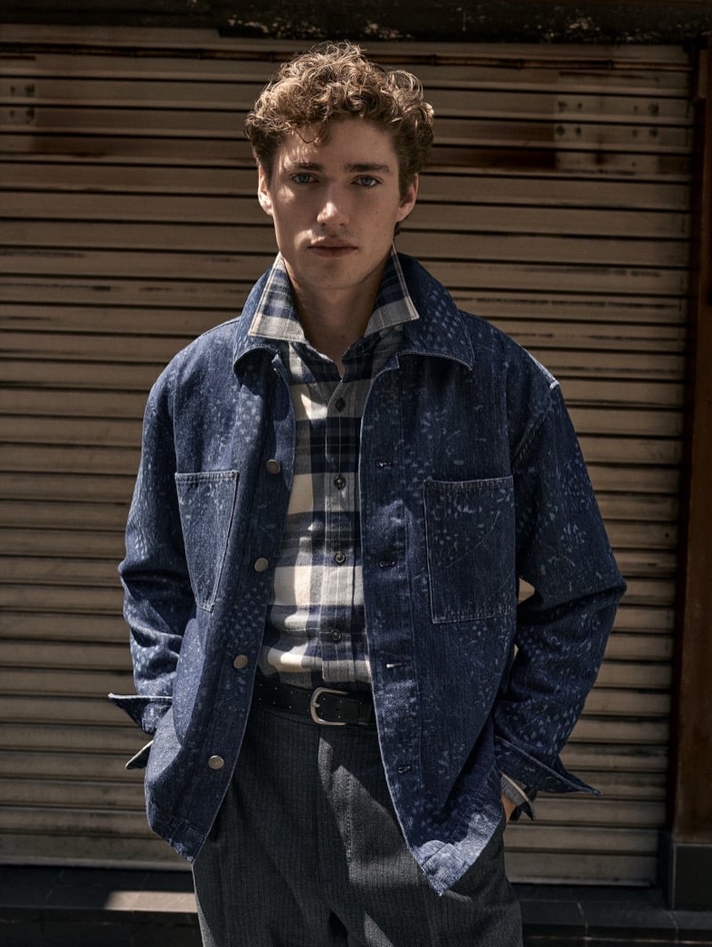 Valentin Humbroich wears a denim chore jacket over a buffalo-check knit with gray pleated trousers for Banana Republic's September 2026 edit