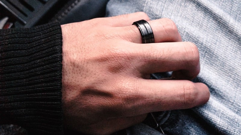 A man's hand resting on denim wearing a black wedding band