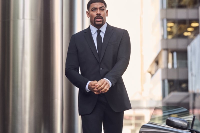 Aaron Pierre wears a black suit with a white shirt and black tie for BOSS' fall-winter 2026 campaign