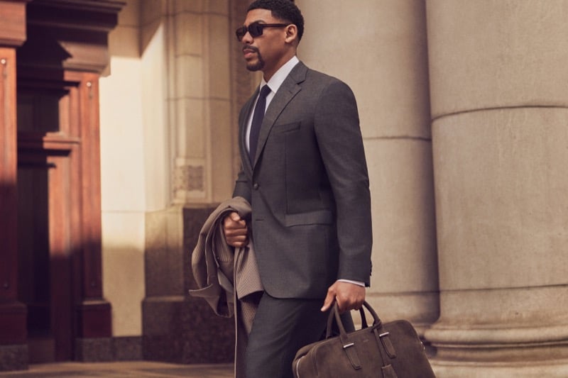 Aaron Pierre wears a charcoal suit and sunglasses while carrying a duffel bag for BOSS' fall-winter 2026 campaign