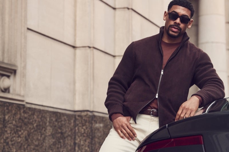 Aaron Pierre wears a brown suede jacket with ribbed knit sleeves and sunglasses for BOSS' fall-winter 2026 campaign