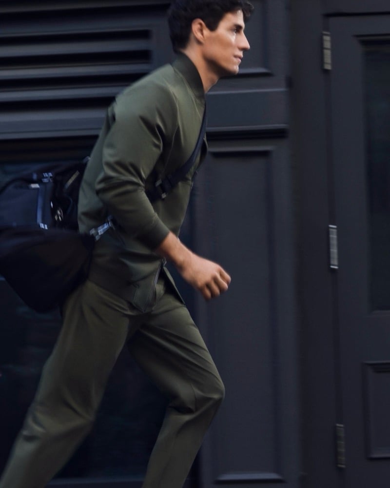 Marcos Fecchino runs down a New York street in an olive zip-front ensemble with a black crossbody bag for BOSS's Performance edit.
