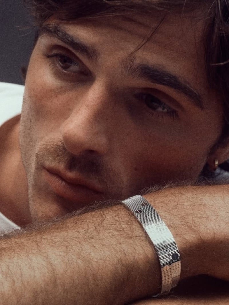 A close crop shows the screw motif on Jacob Elordi's Cartier LOVE Unlimited bracelet as he rests his head against his wrist.