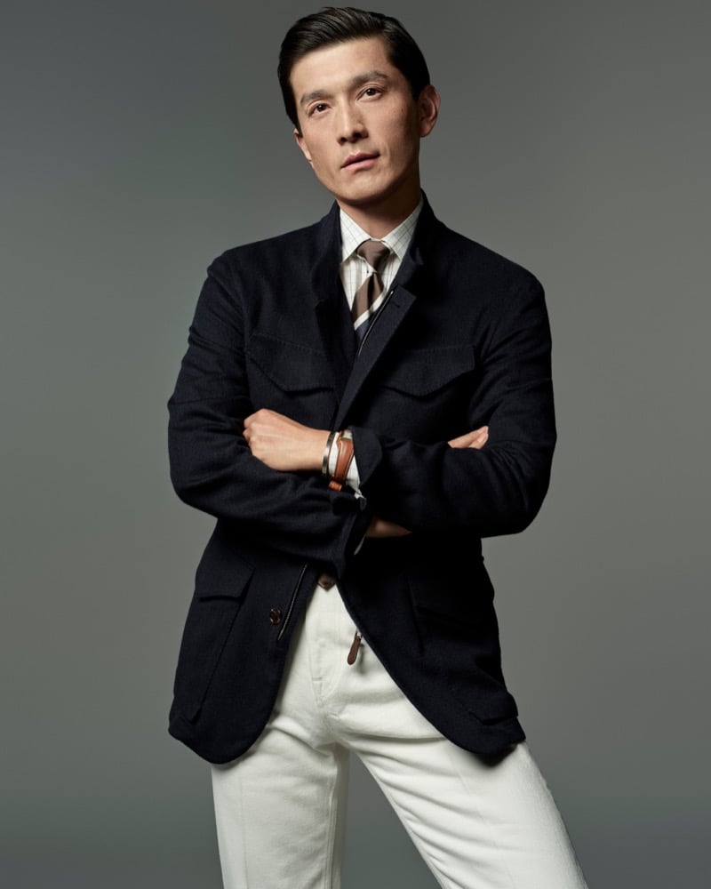 Daisuke Ueda wears a dark field jacket with a striped tie and white trousers for Dunhill's fall-winter 2026 campaign