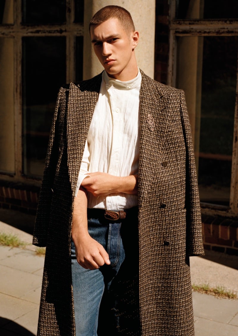 Cameron Phillimore in a long checked tweed coat over a collarless shirt and jeans outside Berlin's Funkhaus for Emporio Armani's fall-winter 2026 campaign