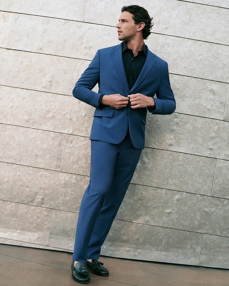 Giacomo Cavalli in a blue suit jacket and black shirt buttoning his blazer