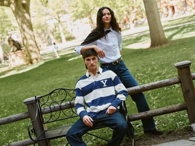 Jack Lumsden seated on a bench in a striped rugby shirt beside a woman in a striped tie and jeans