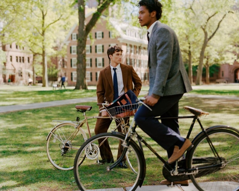 Jack Lumsden and Nile Winchester with bicycles on the Yale campus, one in a brown suit and the other in a gray tweed blazer