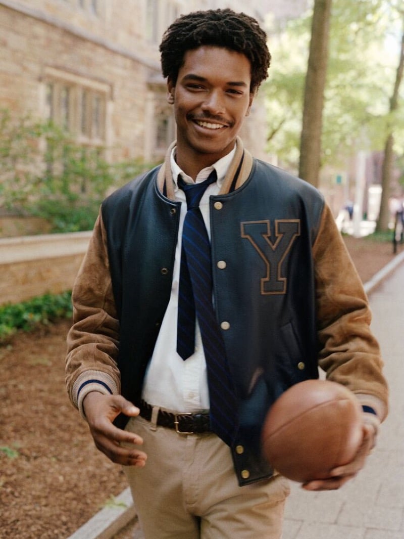 Nile Winchester in a leather varsity jacket with a Y patch, holding a football