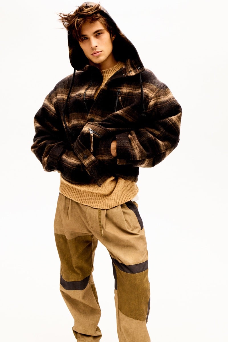 Louis Baines in a plaid hooded jacket over a sweater, wearing patchwork cargo trousers, for Isabel Marant Fall 2026