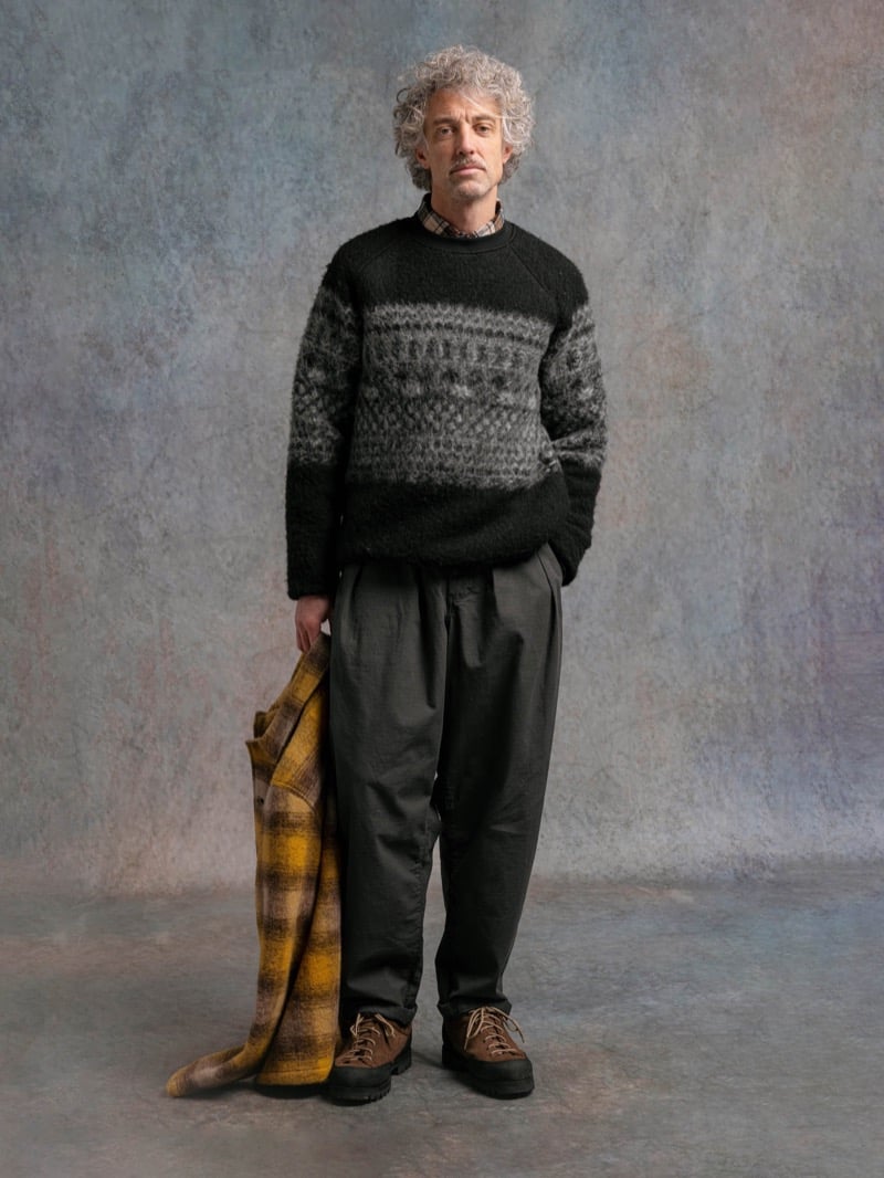 Man in a black and gray Fair Isle sweater, holding a plaid coat, for Kestin Fall 2026