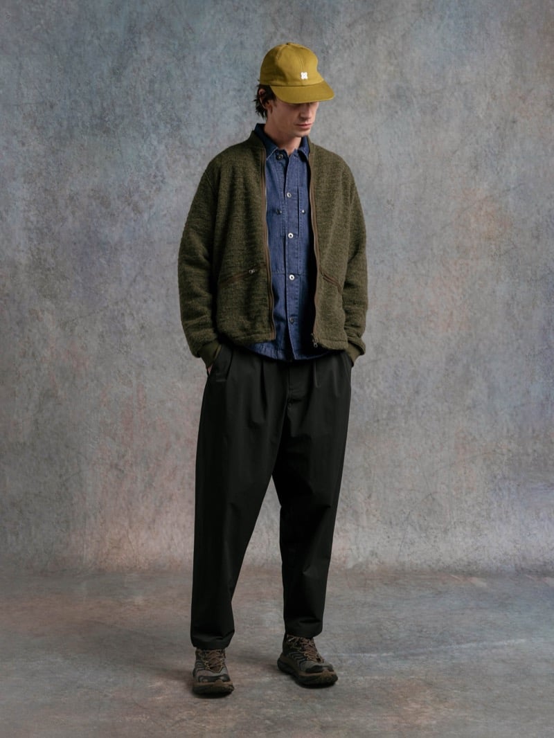 Man in an olive cardigan over a denim shirt, wearing a mustard cap, for Kestin Fall 2026