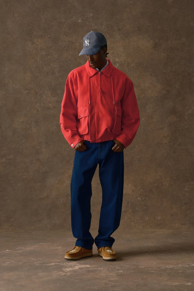 Man in a red zip jacket and blue jeans, wearing a Yankees cap, for Kith Fall 2026