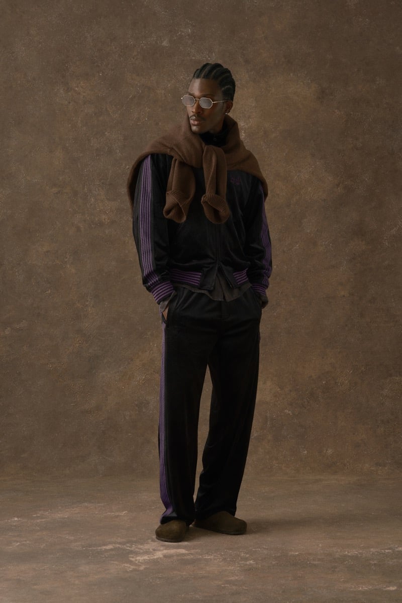 Man in a black velvet track jacket with striped trim, a scarf draped around the neck, for Kith Fall 2026