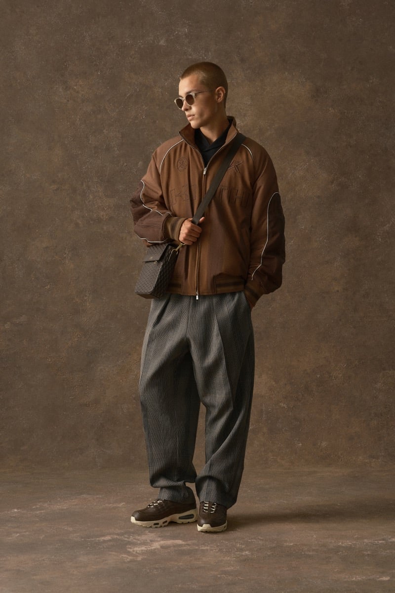 Man in a brown embossed jacket, carrying a crossbody bag over plaid trousers, for Kith Fall 2026