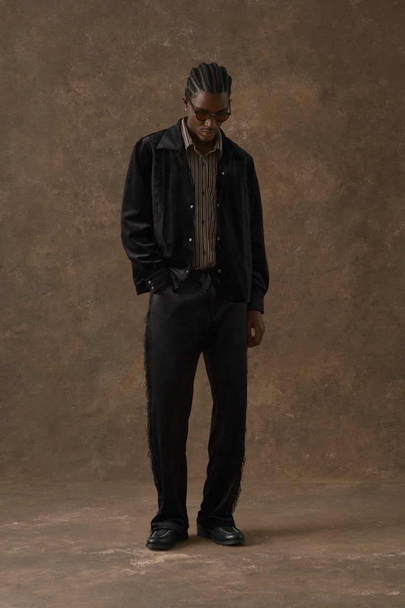 Man in a black velvet jacket over a striped shirt, wearing fringe-trimmed trousers, for Kith Fall 2026