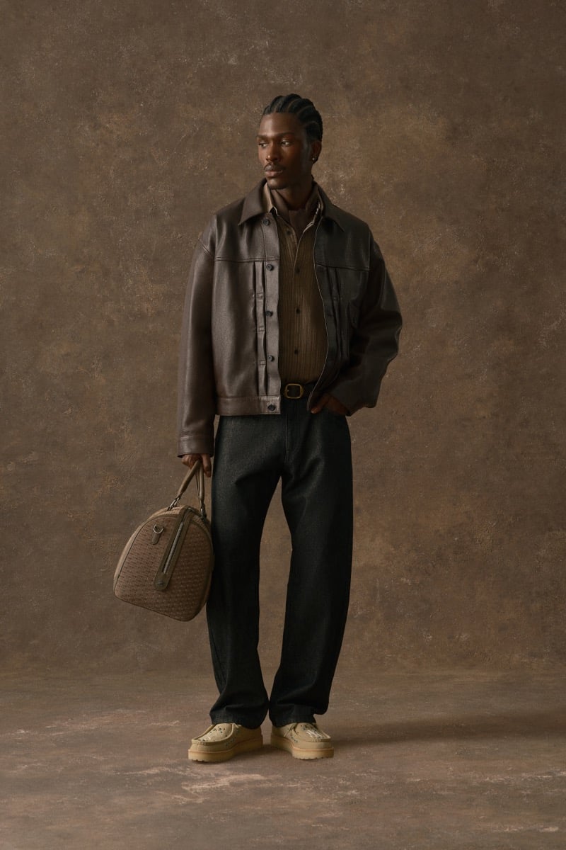 Man in a brown leather jacket over a striped shirt, carrying a woven duffel bag, for Kith Fall 2026