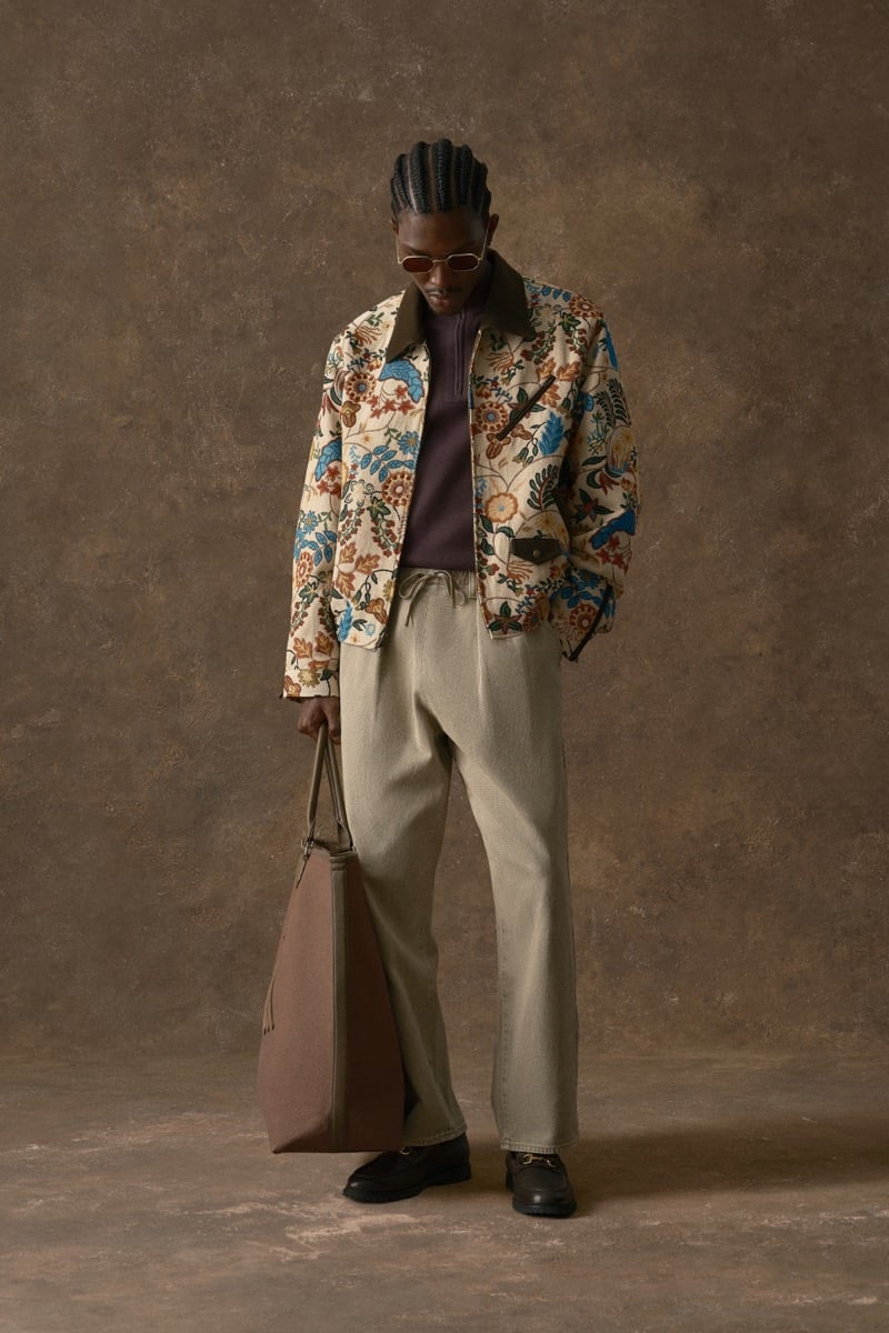 Man in a floral-print jacket over a burgundy quarter-zip, carrying a tote bag, for Kith Fall 2026
