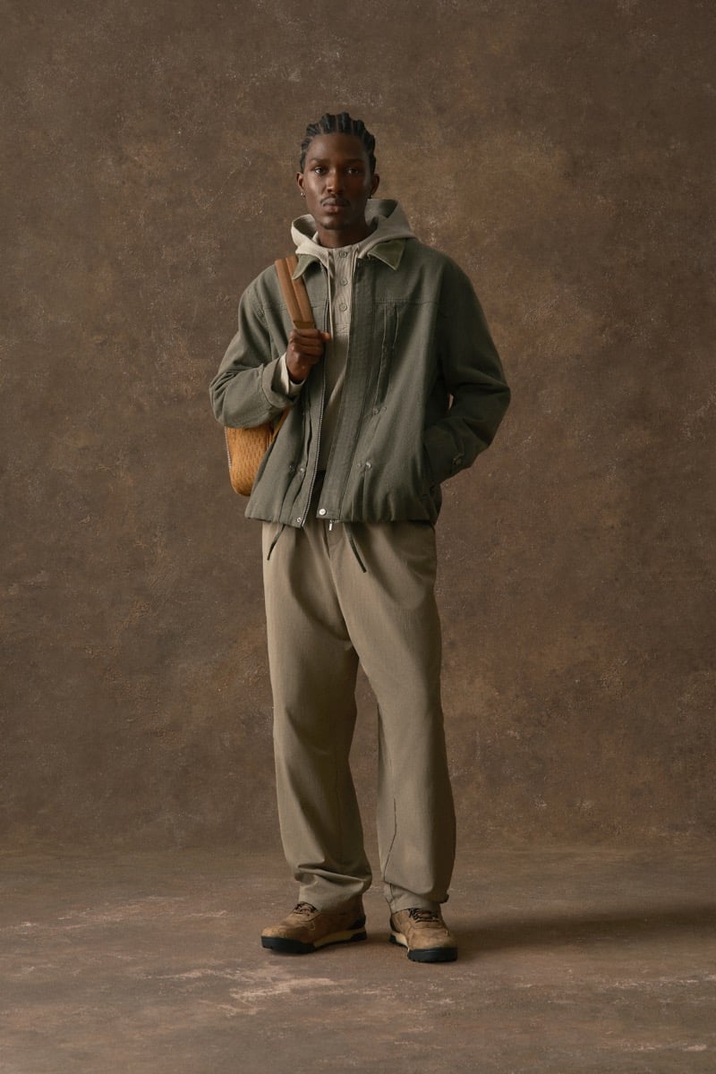 Man in an olive hooded jacket with a contrast collar, carrying a woven bag, for Kith Fall 2026