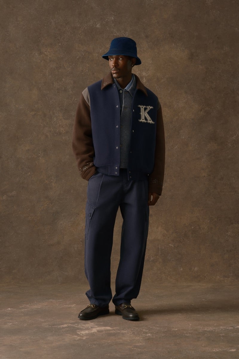Man in a navy varsity jacket with brown leather sleeves and a letterman patch, wearing a bucket hat, for Kith Fall 2026