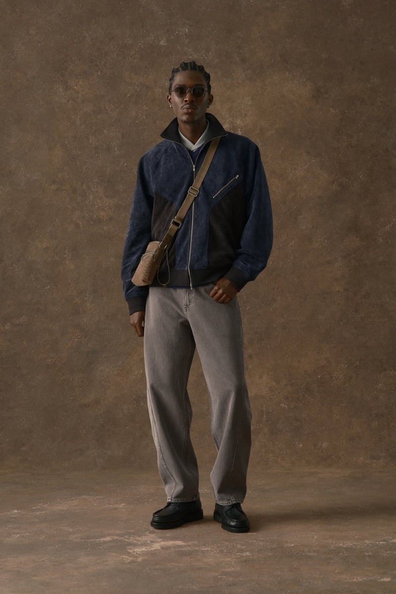 Man in a navy suede jacket, carrying a woven crossbody bag over gray trousers, for Kith Fall 2026