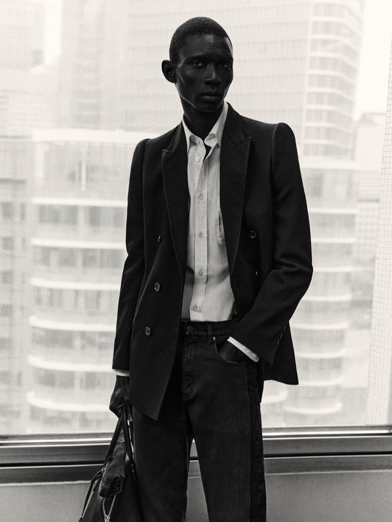 Fernando Cabral in black and white wearing a structured double-breasted Maison Margiela jacket over a shirt and jeans in front of a high-rise window