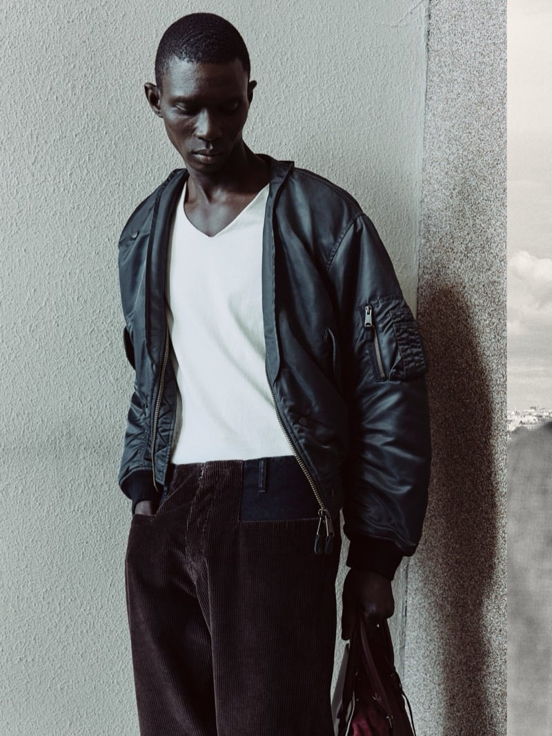 Fernando Cabral wearing a dark Maison Margiela bomber jacket over a light V-neck top and corduroy trousers