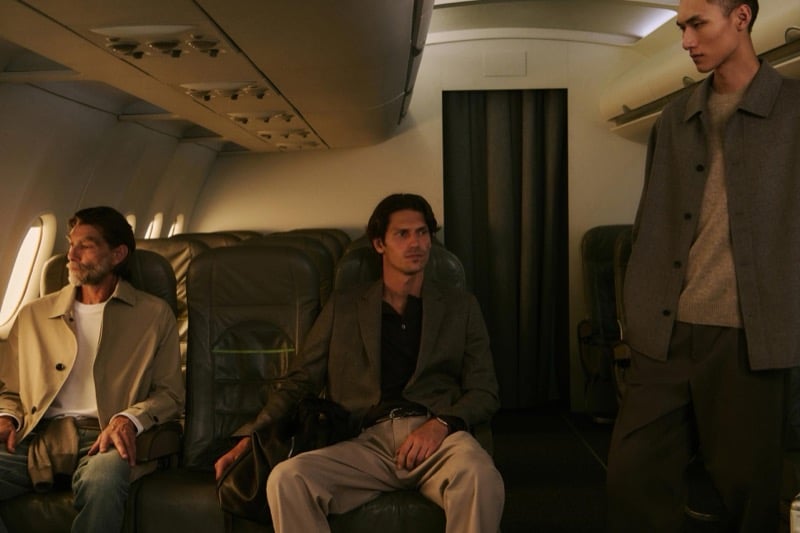 Justin, Patrick, and Siquan sit and stand together in tan and brown outerwear layered over knitwear inside the cabin