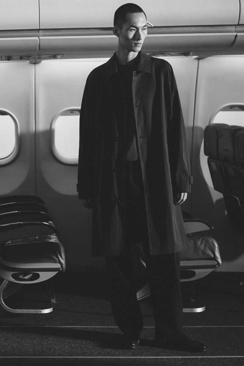 A black-and-white image shows Siquan Wang standing alone in a long coat beside airplane windows
