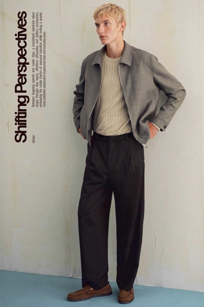 Pierrick Grégoire stands in a gray jacket over a ribbed knit sweater with dark trousers and suede loafers beside the Shifting Perspectives cover text