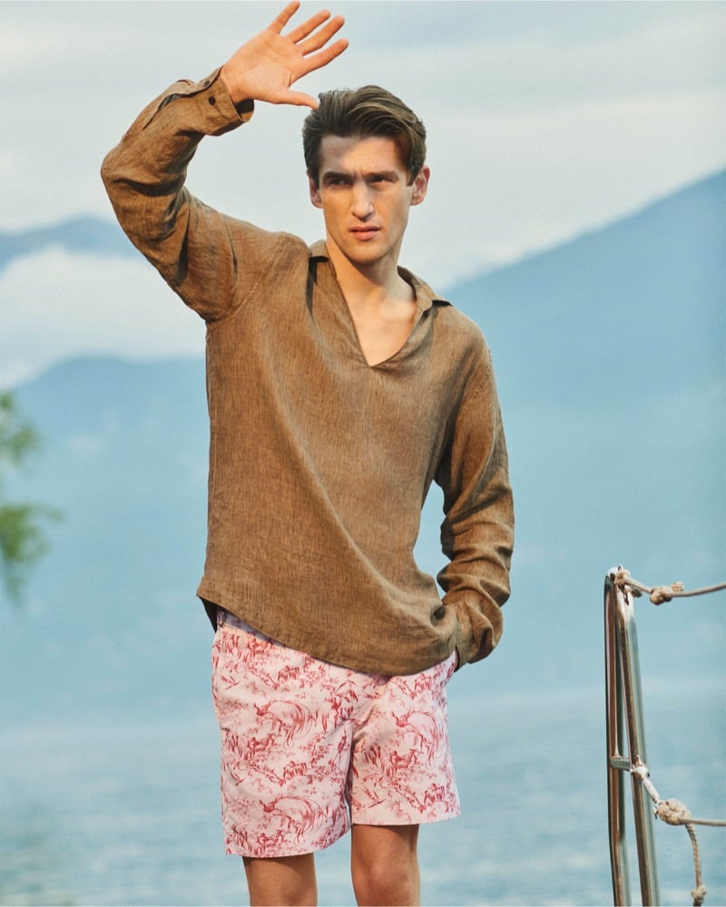 Anatol Modzelewski shields his eyes on a boat wearing a brown popover linen shirt and red toile-print swim shorts