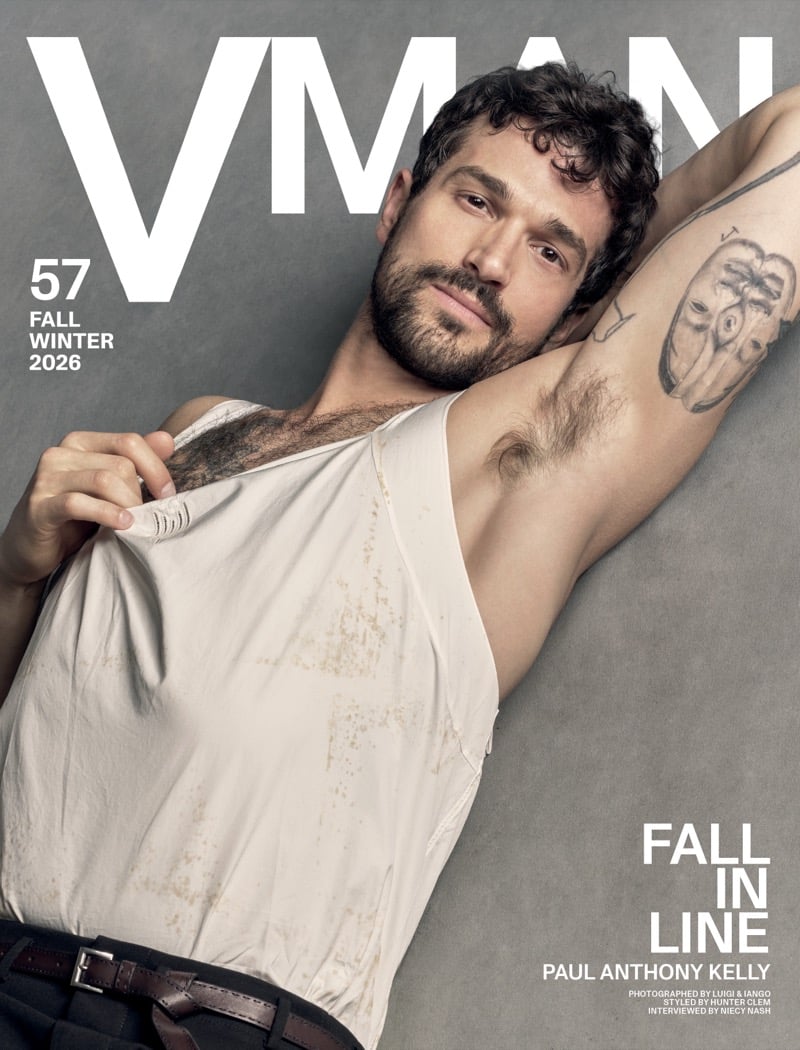 Paul Anthony Kelly on the cover of VMAN's fall-winter 2026 issue, arm raised in a stained Prada tank top with a tattoo visible on his bicep