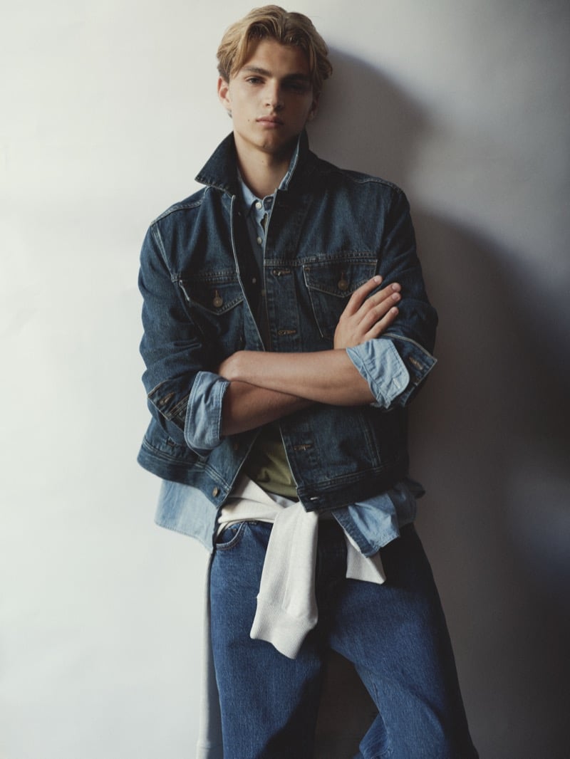 Maurits Scheij in a denim trucker jacket with a sweater tied at his waist, arms crossed