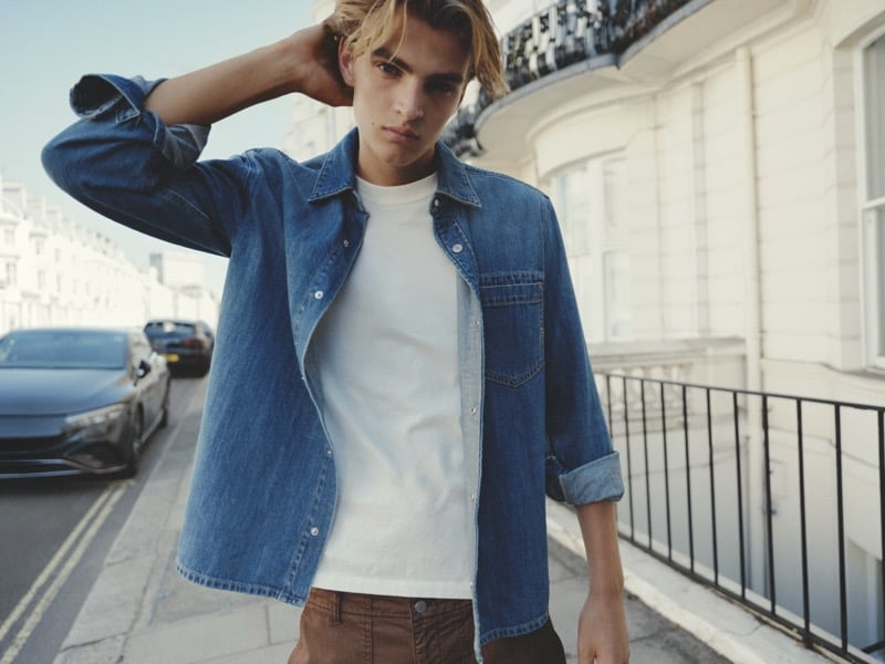 Maurits Scheij in an open denim overshirt over a white T-shirt and brown trousers on a London street