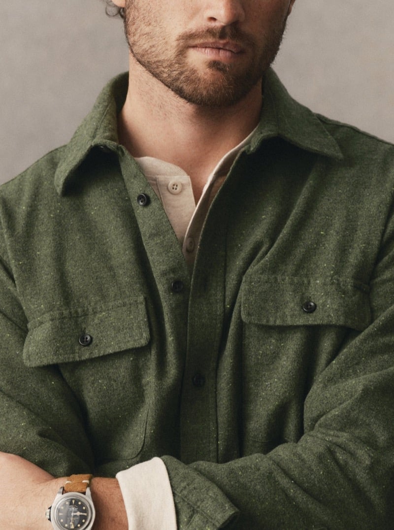 Close-up of a man in an olive wool overshirt layered over a henley with a wristwatch visible, for Taylor Stitch Fall 2026