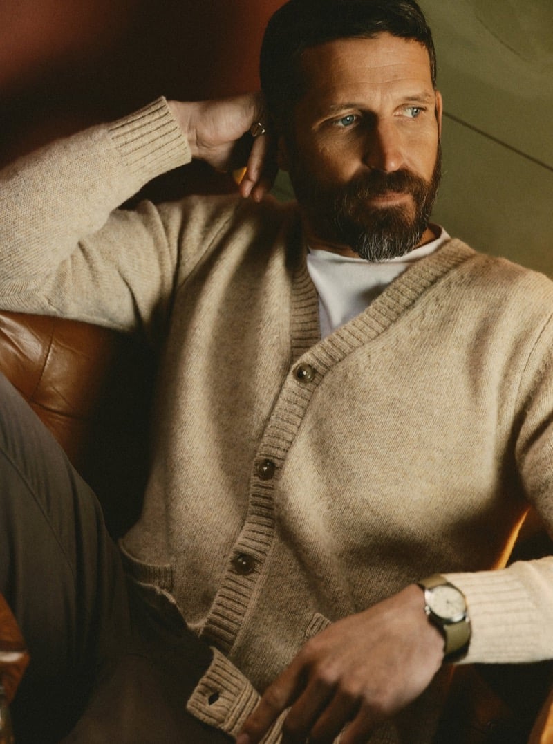 Man in an oatmeal cardigan sweater seated in a leather armchair, for Taylor Stitch Fall 2026