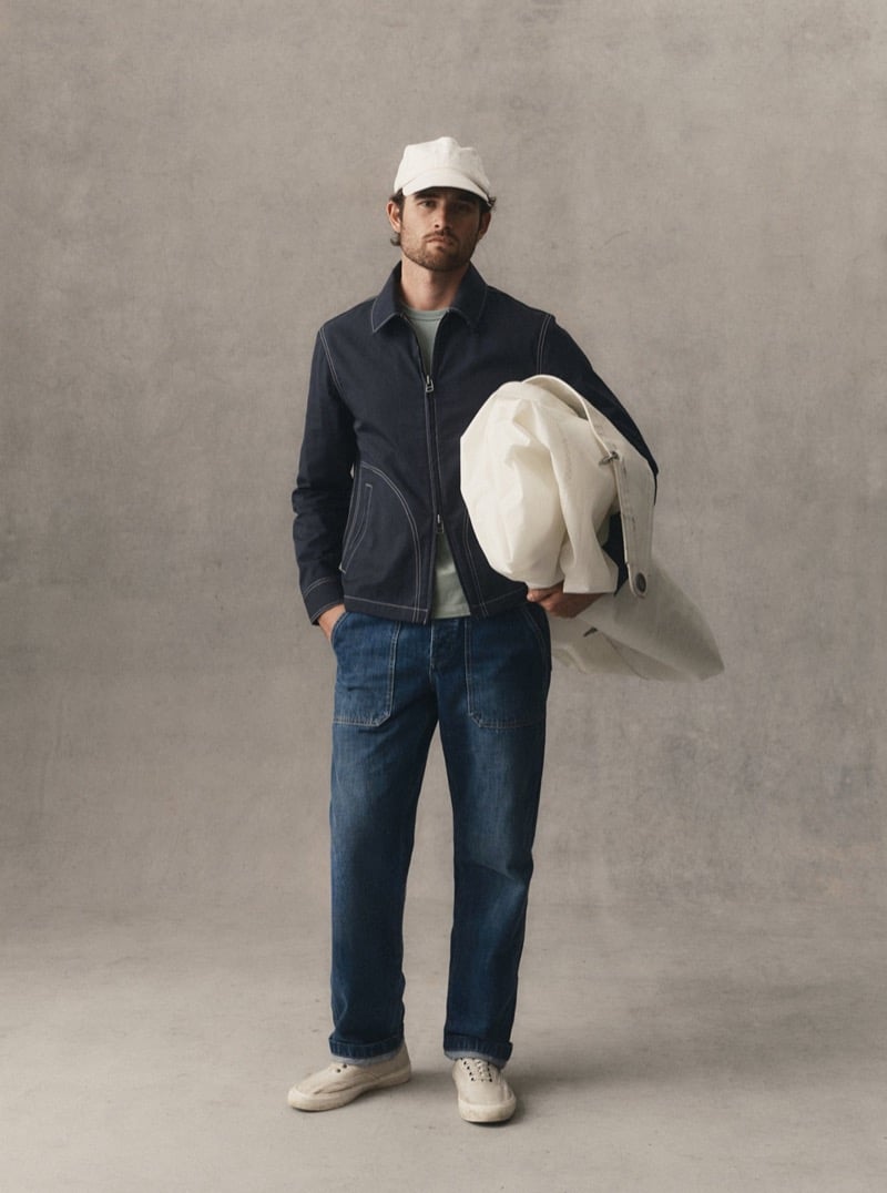 Man in a navy jacket and jeans holding a canvas tote bag in a studio, for Taylor Stitch Fall 2026