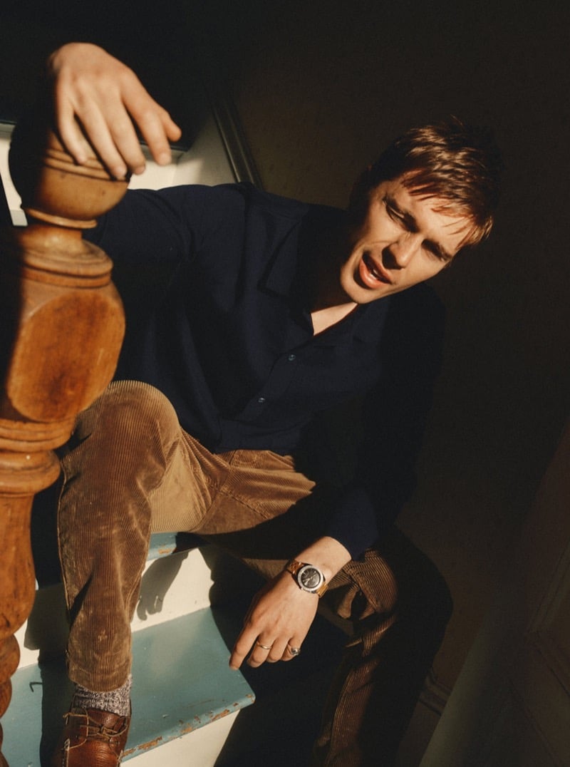 Man in a dark shirt and corduroy pants sitting on a staircase in dramatic light, for Taylor Stitch Fall 2026