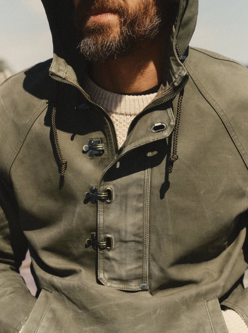 Close-up of a man wearing an olive waxed canvas hooded jacket with metal toggle closures, for Taylor Stitch Fall 2026