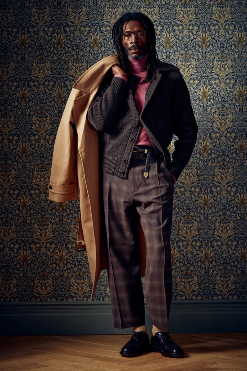 Man in a brown cardigan over a pink turtleneck with a camel coat draped over one shoulder, for Todd Snyder Fall 2026