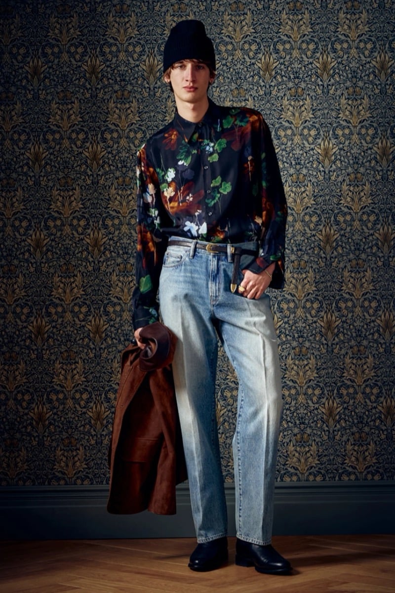 Man in a dark floral shirt and beanie holding a brown suede jacket over jeans, for Todd Snyder Fall 2026