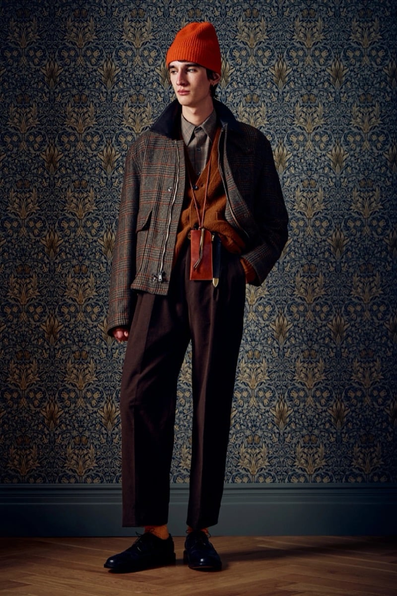 Man in a plaid wool jacket and an orange beanie over a mustard cardigan, for Todd Snyder Fall 2026