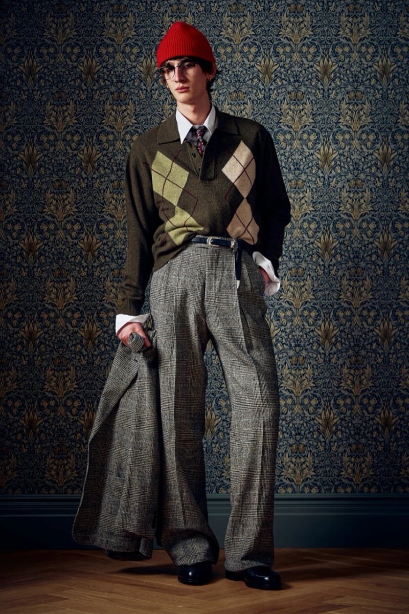 Man in a red beanie and an olive argyle polo sweater with plaid trousers, for Todd Snyder Fall 2026
