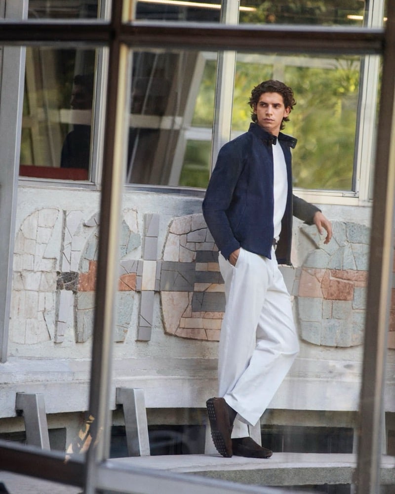 Hedi Ben Tekaya in a navy suede jacket, white t-shirt, and trousers, wearing brown suede driving shoes