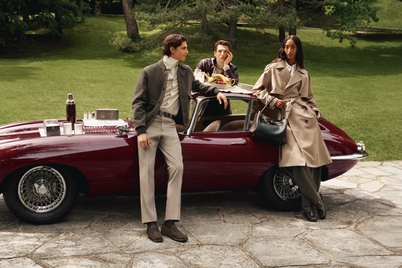 Hedi Ben Tekaya in a wool blouson, Anatol Modzelewski in a leather jacket, and Mona Tougaard in a trench coat beside a vintage sports car on the villa lawn for Tod's fall-winter 2026 campaign