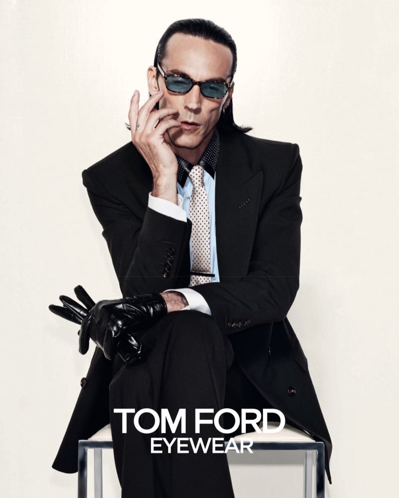 Scott Barnhill wears tortoiseshell sunglasses, a leather glove, and a polka-dot tie over a pale blue shirt with a dark suit for Tom Ford's fall-winter 2026 eyewear campaign
