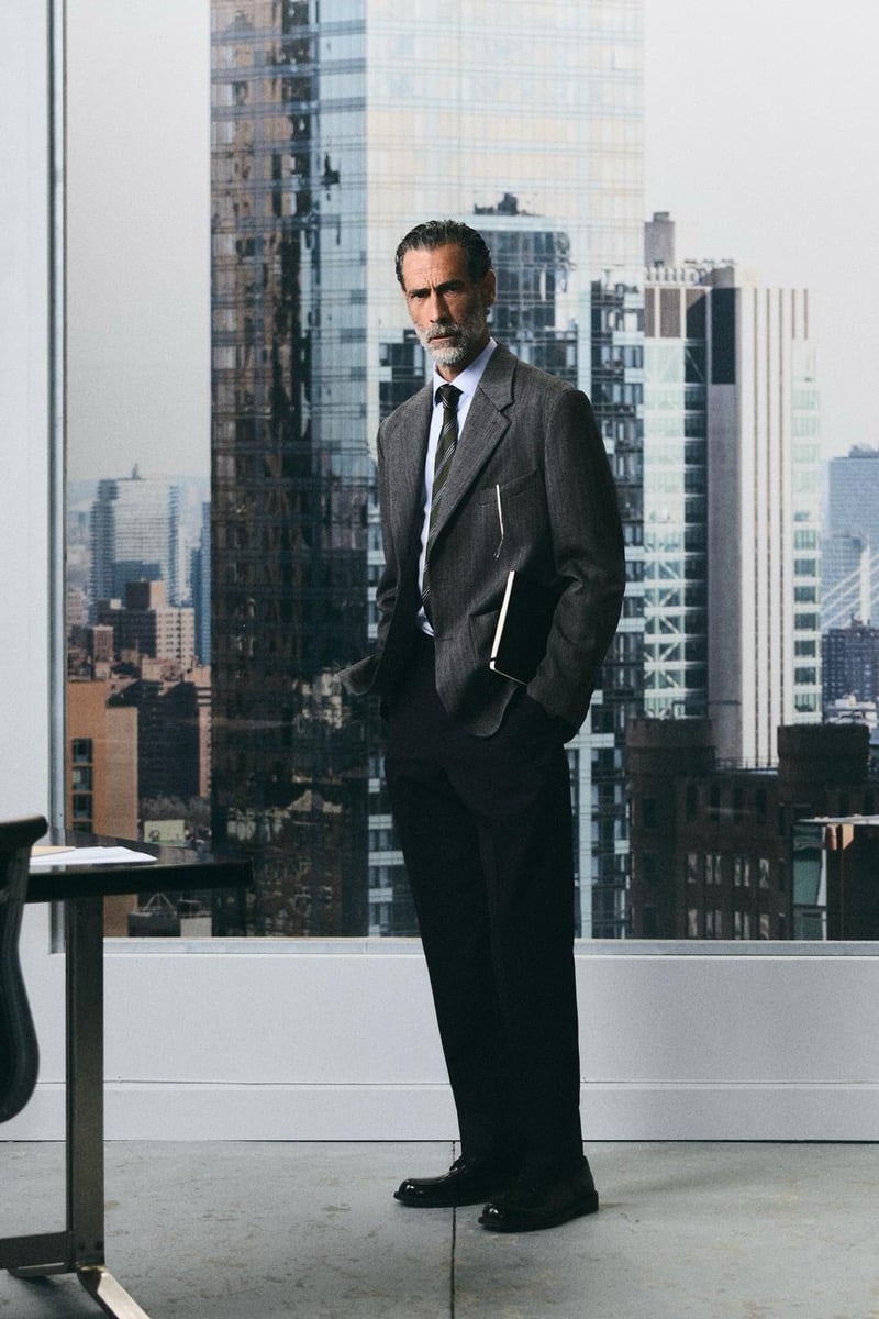 John Armstrong wears a gray blazer with a striped tie in front of a city skyline for Zara's back to work 2026 campaign