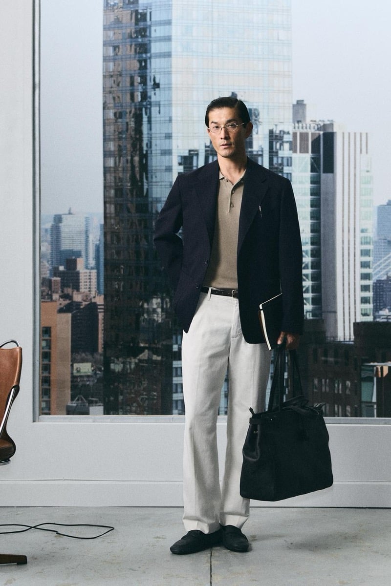 Daisuke Ueda wears a navy blazer with a tan polo and light gray trousers, a notebook and tote bag in hand, for Zara's back to work 2026 campaign