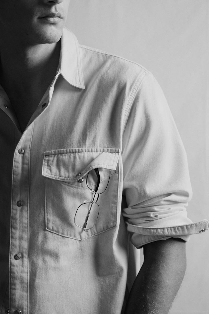 Black and white close-up of a chest pocket with sunglasses tucked inside a chore shirt