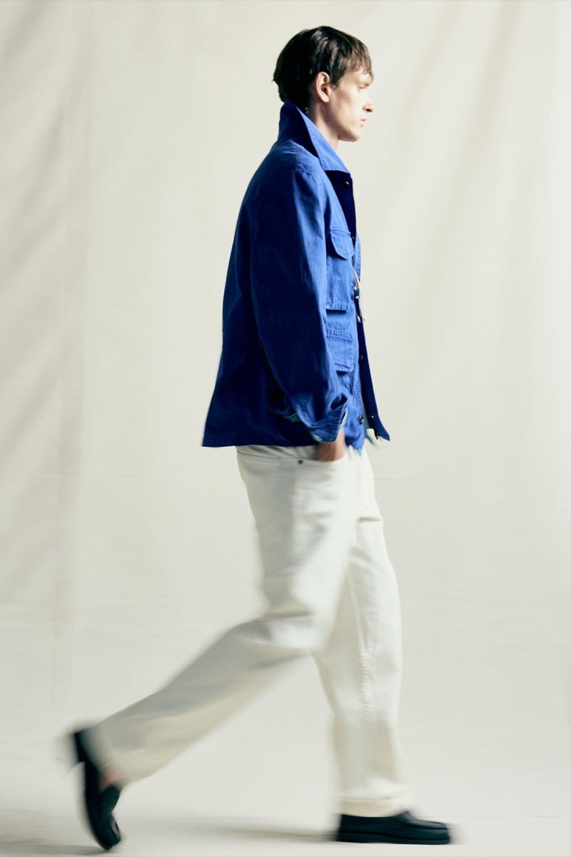 Jegor Venned walking in a cobalt utility jacket and light trousers, motion blur